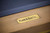 Plank & Hide Co Plank & Hide Deco 8' Slate Pool Table in Glazed Maple, close-up of the gold metal plaque with brand label on the wooden frame.