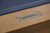 Plank & Hide Co Isaac 8' Slate Pool Table in Glazed Maple, close-up of the metal brand plate on the wooden frame.