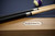 Plank & Hide Co Isaac 8' Slate Pool Table in Glazed Maple, close-up of the wooden table with steel corner details and billiard cues resting on top.