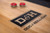 Detail view of the Doc & Holliday logo inlaid on the maple butcher block shuffleboard playfield of the Savant table, highlighting the natural wood grain and precision craftsmanship.