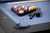 Doc & Holliday Redford Slate Pool Table in Matte Black, close-up of pool table with blue felt, pool balls, cue, and black corner pocket.