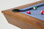 Doc & Holliday The Bellano Slate Pool Table in Matte Brandwine, close-up of the corner with a brown wood finish and blue felt surface with pool balls.