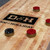Doc & Holliday George Pool Table & Shuffleboard Set in Glazed Maple, close-up of the wooden surface with shuffleboard pucks and logo.
