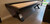 Sawyer Twain Maverick Shuffleboard Table, modern black shuffleboard table with wooden playing surface and sleek angular legs, available with free installation in the USA.