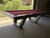 Sawyer Twain Matrix Outdoor Slate Pool Table with Sunbrella Felt, made in USA, featuring a sleek black frame, red felt surface, and modern angled legs for outdoor recreational use.
