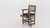Plank & Hide Co Spectator Chair, wooden chair with armrests and a black cushioned seat, featuring a built-in pocket for buying accessories and a slot for loads, with a pool cue leaning against the chair.