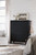 Hooker Furniture Hamrick Club Chair, a stylish black wooden dresser with brass handles, topped with a glass vase of white flowers and a framed black and white landscape photograph in a cozy bedroom decor.