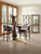 Hooker Furniture Curata Bunching Bookcase, modern living room with two gold bookcases displaying decorative items and a dining area with a round table and chairs.