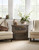 Hooker Furniture Sanctuary Spindle Back Arm Chair, two beige upholstered arm chairs with nailhead trim flanking a wooden side table with decorative vases and a large potted plant in a bright, airy room