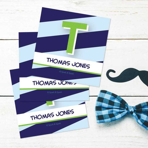 SparkGreetings® Brilliant Initial Blue Gift Label Set, personalized name labels with initial T and the name Thomas Jones on a white wooden background.