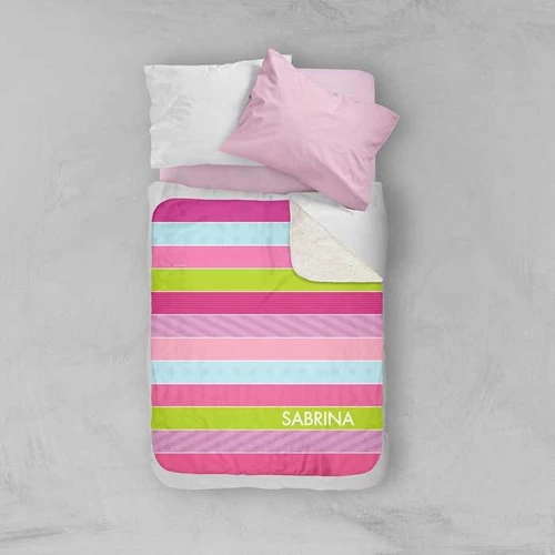 Spark & Spark Sweet Lines Sherpa Blanket, colorful striped patterned blanket with personalized name Sabrina, folded at the corner, placed on a bed with pink and white pillows.