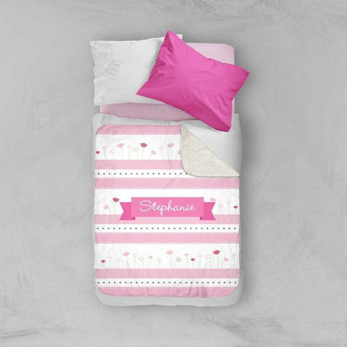Spark & Spark Cute Tulips Sherpa Blanket, pink and white customizable blanket with floral design and a personalized name label, laid on a bed with pillows.