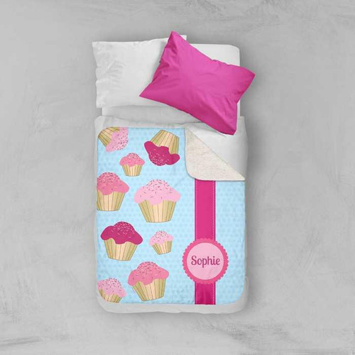 Spark & Spark Sweet Cupcakes Sherpa Blanket, personalized with the name Sophie, featuring colorful cupcake illustrations on a light blue background with pink accents.