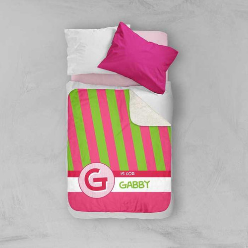 Spark & Spark Double Initial & Stripes Pink Sherpa Blanket, pink, green, and white striped blanket with personalized name GABBY, on a bed with pillows.
