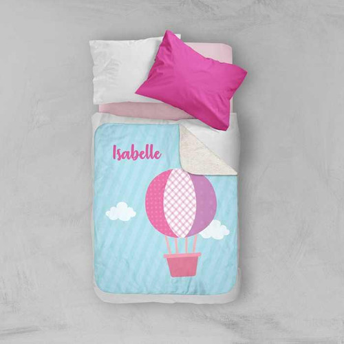 Spark & Spark Pink Hot Air Balloon Sherpa Blanket, pink hot air balloon with clouds and personalized name 'Isabelle' on a light blue background.