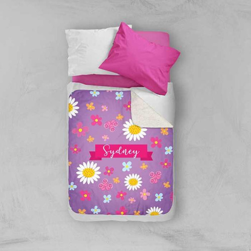 Spark & Spark Field Of Flowers Purple Sherpa Blanket, a colorful floral blanket with daisies, pink, blue, and yellow flowers, personalized with the name Sydney.