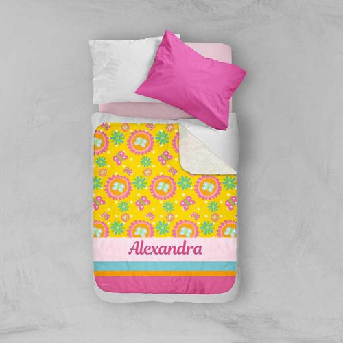 Spark & Spark Flower Initial Sherpa Blanket, personalized colorful floral and striped blanket with the name 'Alexandra' embroidered, on a bed with pillows.