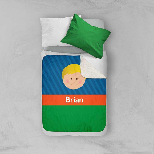 Spark & Spark Just Like Me Boy Blue Sherpa Blanket, blue and green blanket with a cartoon face and the name Brian printed on it, on a bed with white sheets and a green pillow.