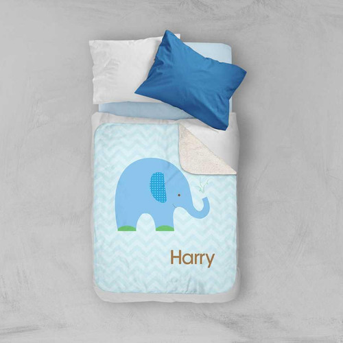 Spark & Spark Blue Baby Elephant Sherpa Blanket, blue elephant design with green accents and personalized name Harry, on a bed alongside blue and white pillows.