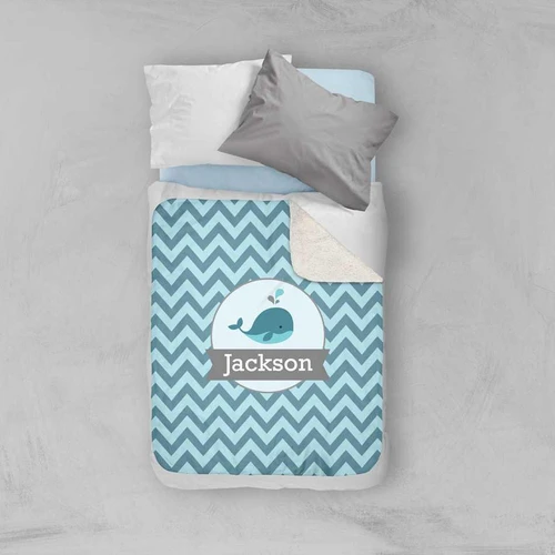 Spark & Spark Sweet Little Blue Whale Chevron Sherpa Blanket, personalized with the name Jackson, on a bed with pillows.