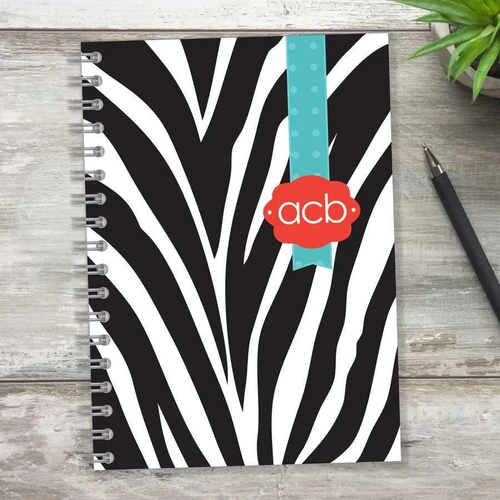 SparkGreetings® Zebralicious Writing Journal, a black and white zebra print spiral notebook with a blue and red ribbon label.