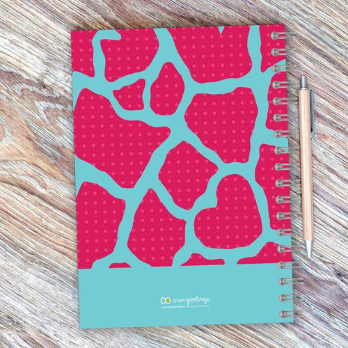 SparkGreetings® Cute Rocks Writing Journal, colorful notebook with pink and blue abstract design and spiral binding on wooden surface with pen
