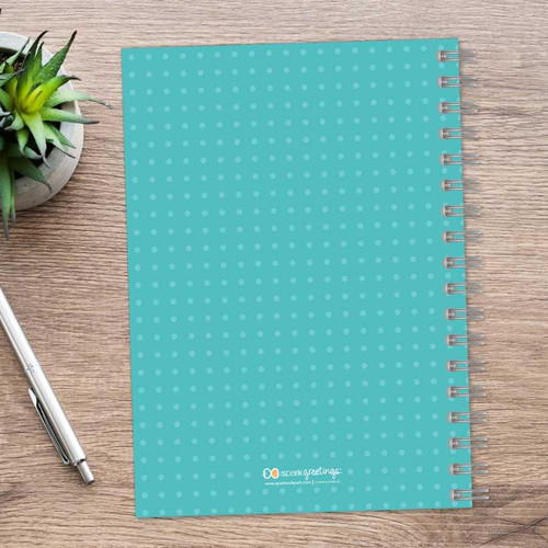 SparkGreetings® Mod Chevrons Writing Journal, blue dotted cover spiral-bound notebook on wooden desk with silver pen and green succulent plant.