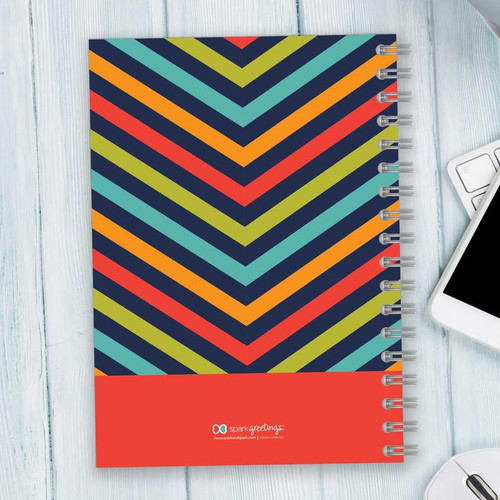 SparkGreetings® Style in Stripes Writing Journal, vibrant multicolored striped design with spiral binding on white wooden surface.
