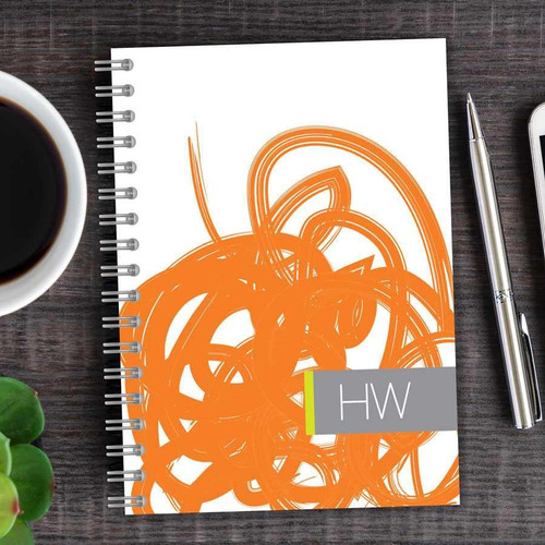 SparkGreetings® Urban Graffiti Writing Journal, spiral-bound notebook with orange graffiti-style cover design on a wooden desk.