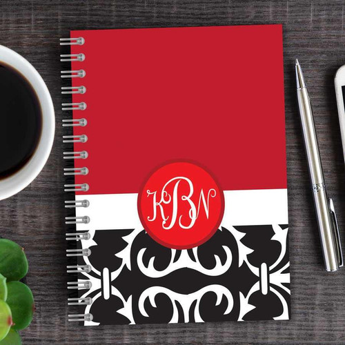 SparkGreetings® Victorian Bold Style Writing Journal, featuring a red, white, and black ornate cover design with monogram initials, on a wooden desk with a cup of coffee, a silver pen, and a smartphone.