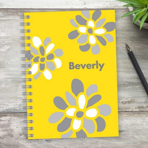 SparkGreetings® Stamped Blossoms Writing Journal, personalized yellow notebook with white and gray flower designs and the name Beverly on the cover.