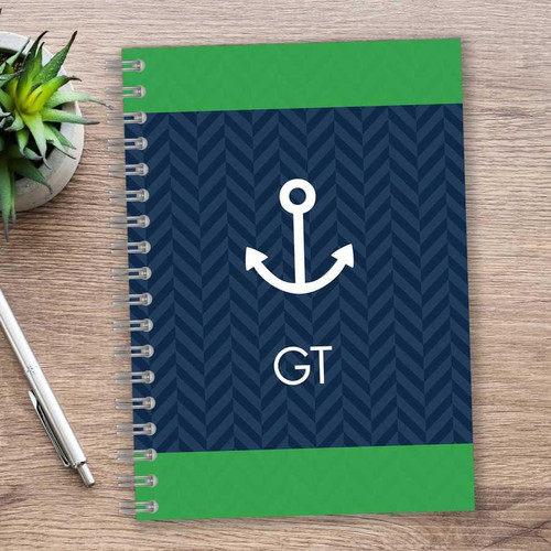 SparkGreetings® Nautical Anchor Writing Journal, navy blue and green cover with anchor graphic and initials GT on a wooden desk with a silver pen and potted succulent plant.