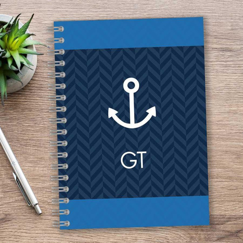 SparkGreetings® Nautical Anchor Writing Journal, navy blue notebook with white anchor graphic and initials GT, spiral-bound on wooden desk.