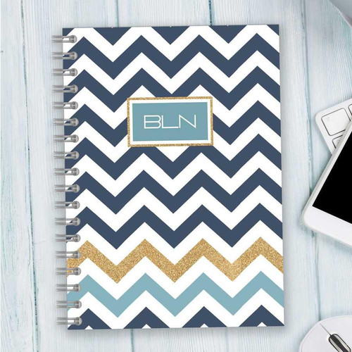 SparkGreetings® Blue Chevron Writing Journal, spiral-bound notebook with navy, gold, and blue chevron pattern cover and monogram 'BLN' on the front.