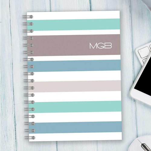 SparkGreetings® Array of Stripes Writing Journal, a spiral-bound notebook with pastel-colored horizontal stripes on the cover.