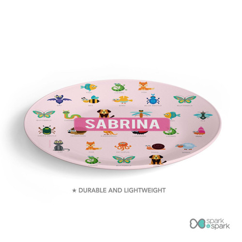 Spark & Spark Animal ABC Pink Custom Plate for Girls, pink round plate with colorful animal alphabet illustrations and the name 'Sabrina' in the center.