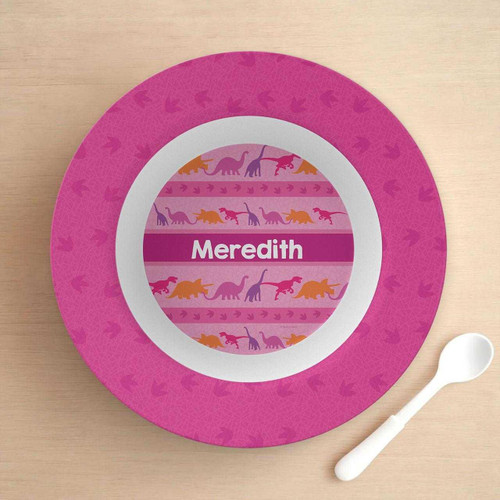 Spark & Spark Dinosaur Trails Girl Kids Bowl with personalized pink and purple dinosaur design and the name Meredith, on a light wooden surface with a white spoon beside it.