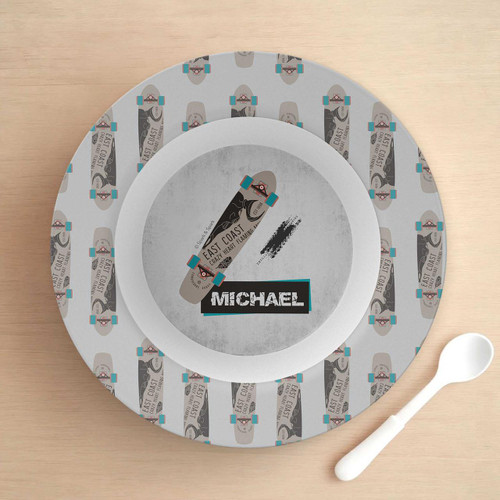 Spark & Spark Urban Skate Grey Kids Bowl, a round grey skateboard-themed bowl with colorful skateboard graphics and the name 'Michael' printed on it, placed on a wooden surface with a white spoon beside it.
