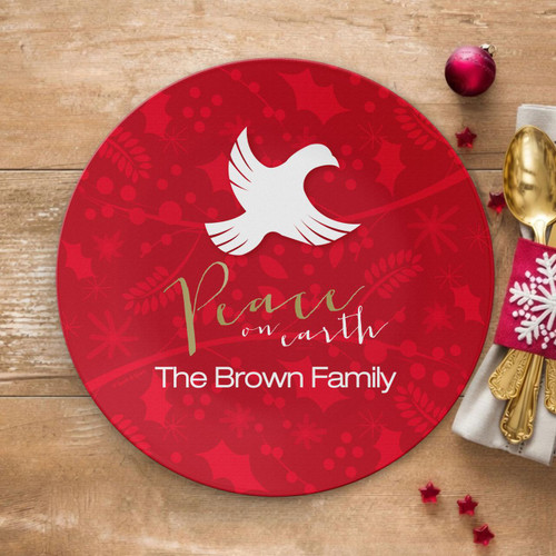 Spark & Spark Peace On Earth Holiday Placemat, red holiday-themed placemat with white dove logo, decorative holly and snowflake patterns, personalized with 'Peace on earth The Brown Family'.