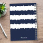 SparkGreetings® Radio Signals Writing Journal, navy blue and white striped torn-paper design cover with spiral binding, placed on a wooden surface with a pen and a green succulent plant nearby.
