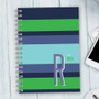SparkGreetings® Bold and Modern Writing Journal, featuring a colorful striped cover with the letter R and the text 'is for Robyn' on a light-colored wooden desk.