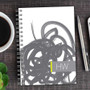 SparkGreetings® Urban Graffiti Writing Journal, spiral-bound journal with abstract graffiti design on the cover, placed on a wooden desk next to a cup of coffee and a silver pen.