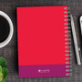 SparkGreetings® Urban Graffitti Writing Journal, red notebook with purple accent at the bottom, spiral binding, with a pen, on a wooden desk.