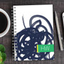 SparkGreetings® Urban Graffiti Writing Journal, electronic graffiti design on a white cover with a green 'HW' label, placed on a wooden desk with a cup of coffee and a silver pen.