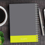 SparkGreetings® Urban Graffiti Writing Journal, front cover with gray and yellow design, spiral binding, placed on a wooden desk with a cup of coffee, a green plant, and a pen.