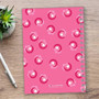 SparkGreetings® Small Swirls Writing Journal, pink pages with a floral swirl pattern, spiral-bound notebook on wooden surface with pen and plant nearby.