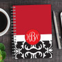 SparkGreetings® Victorian Bold Style Writing Journal, featuring a red, white, and black ornate cover design with monogram initials, on a wooden desk with a cup of coffee, a silver pen, and a smartphone.
