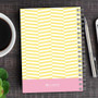 SparkGreetings® Up and Down Style Writing Journal, yellow and pink zigzag patterned notebook with spiral binding on a wooden desk, with a cup of coffee, pen, and smartphone nearby.