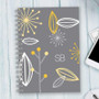 SparkGreetings® Deconstructed Nature Writing Journal, stylish gray journal with yellow, white, and gray botanical-themed abstract leaf and flower designs, monogrammed with initials SB on the cover.