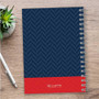 SparkGreetings® Nautical Anchor Writing Journal, navy blue cover with a red bottom section featuring a white logo and text, spiral-bound notebook on a wooden desk with a pen and a small green plant nearby.